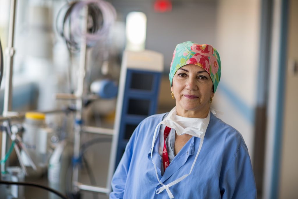 A perfusionist stands in portrait in full hospital attire