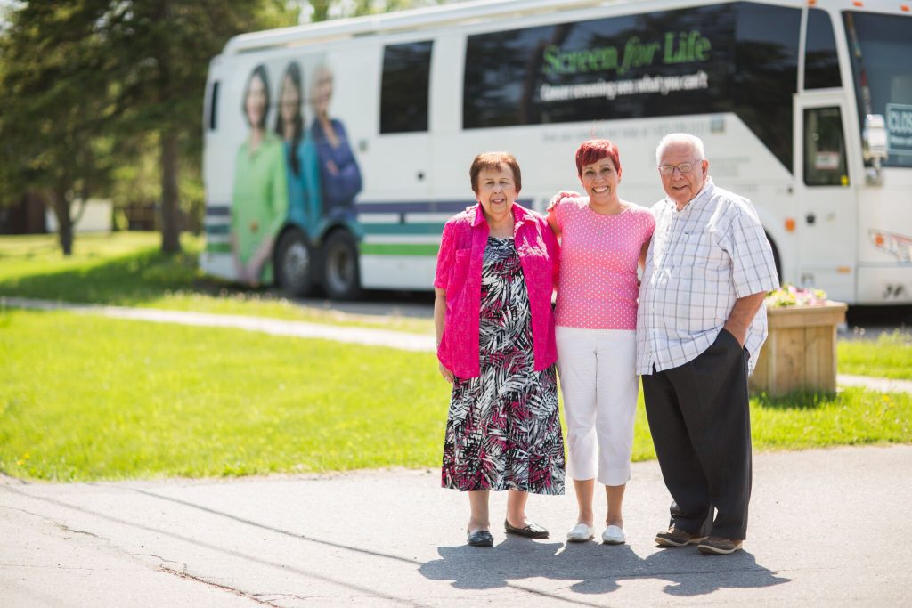 Dr. Amy Montour stands in front of the Mobile Cancer Screening Coach with her parents