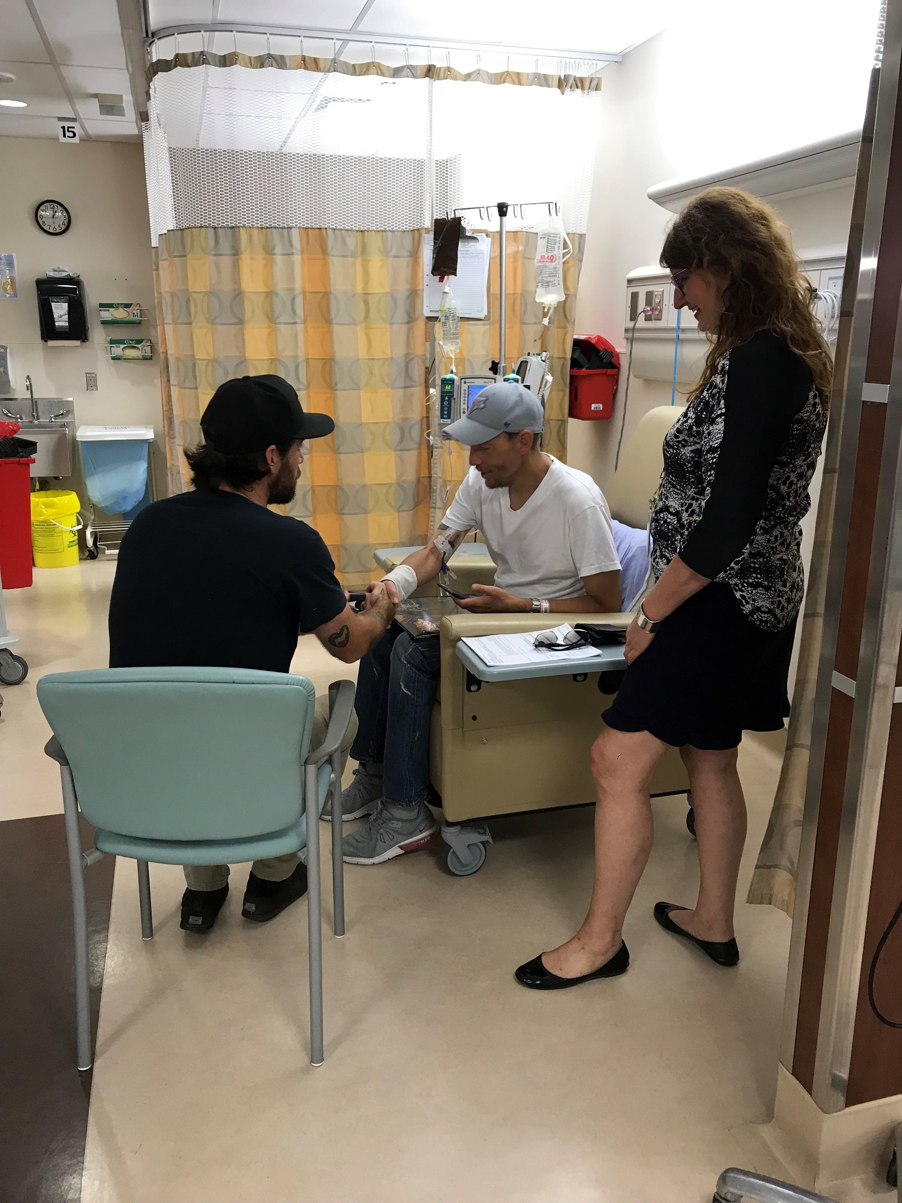 Steve Kiely sits in a hospital room talking to Darrell