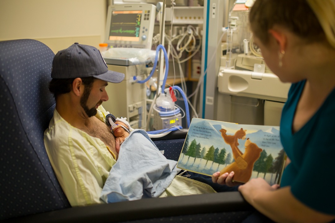 Parents read to their newborn child in the NICU