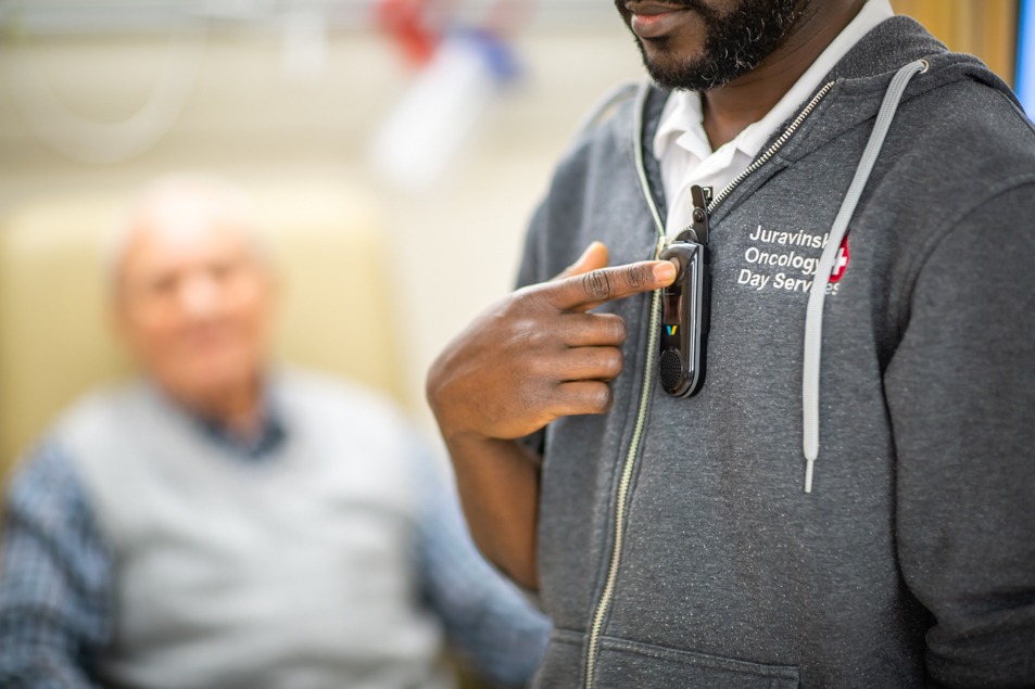 A nurse presses a button on his communication device
