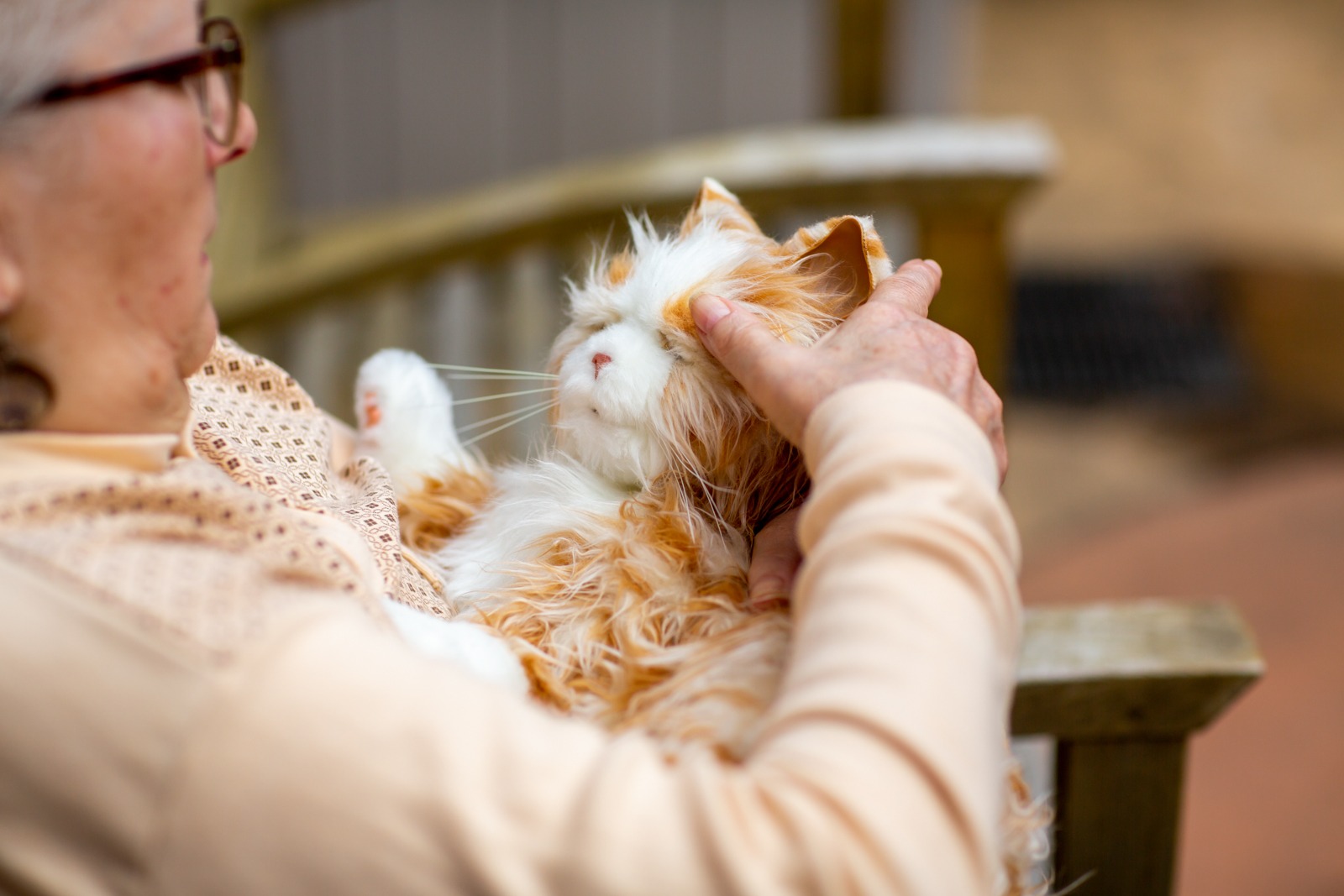 an orange robotic cat being petted in a woman's lap