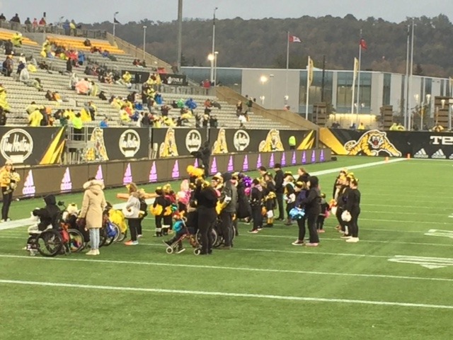 the squad cheering on the football field in the rain at Tim Horton's Field
