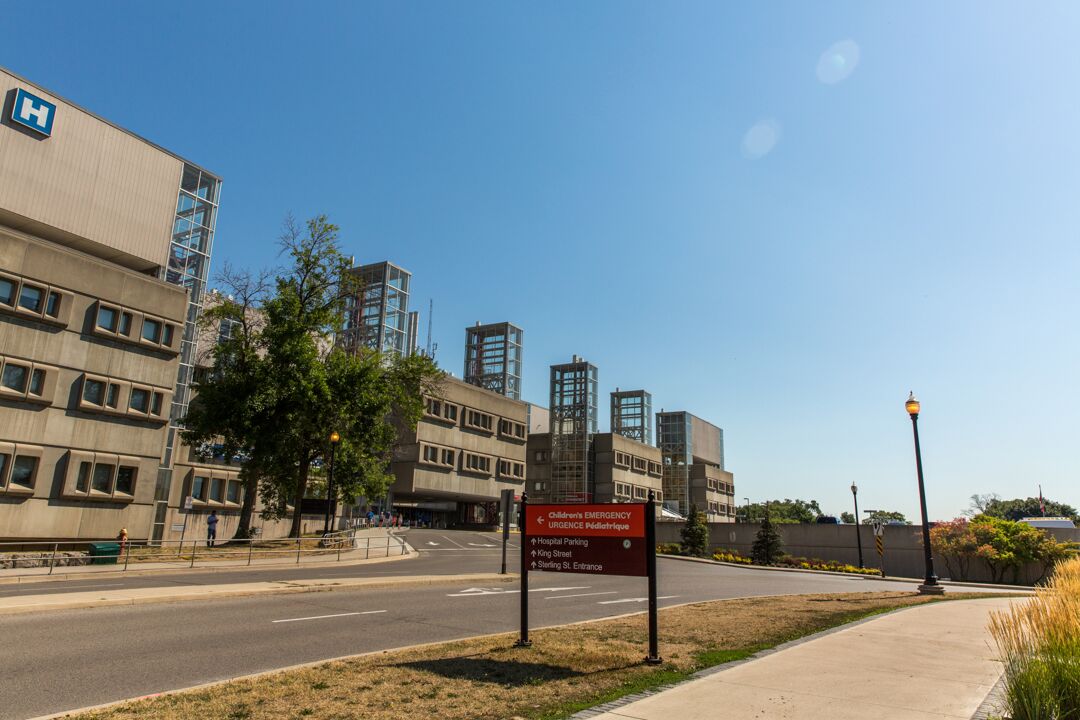 An exterior photo of McMaster University Medical Centre, a large, cement building, with a blue sky in the background