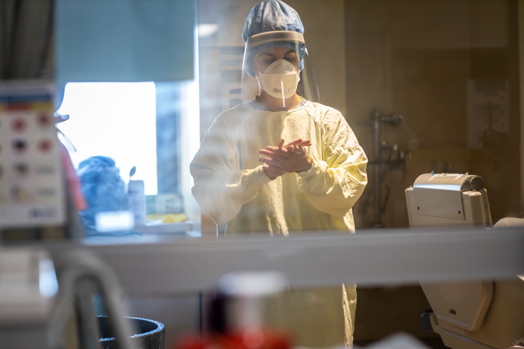 An ICU staff member washes their hands before leaving the room.
