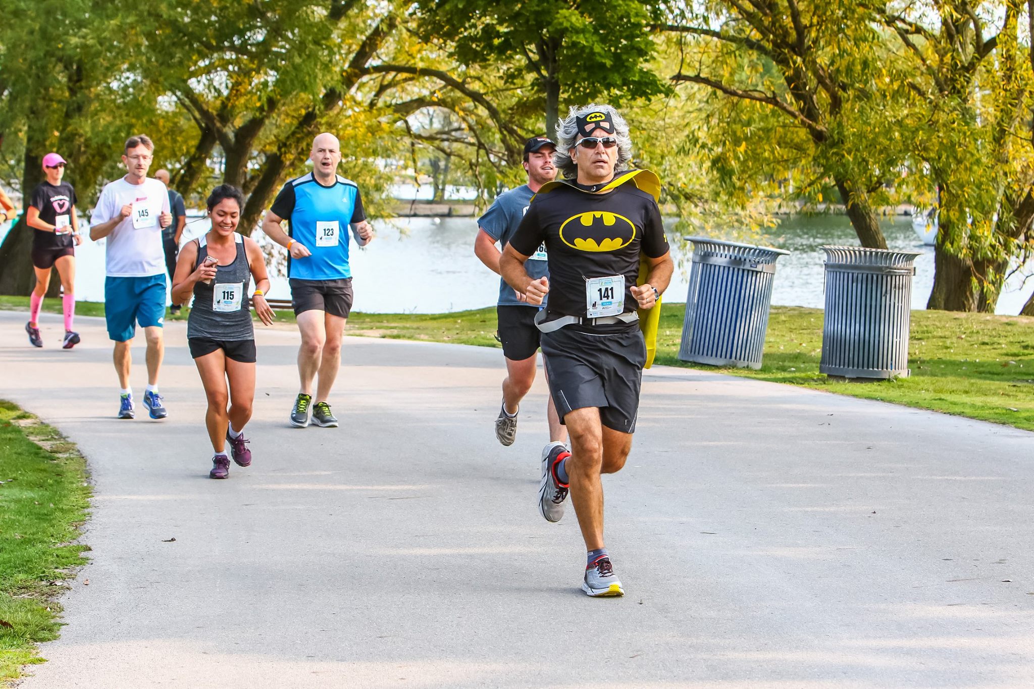 Peter running in a Batman costume. There are other runners behind him.