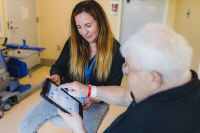 Researcher Dr. Courtney Kennedy demonstrates the Fit-Frailty app for a patient.