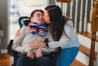 Meric in a wheelchair and his mom Lisa kissing his cheek