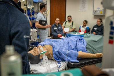 High fidelity simulation lab representing an operating room. Students engage in a discussion after a simulated general anesthetic demonstration.