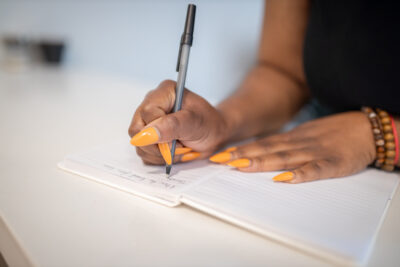 Moyo's hands holding a pen, writing in a journal